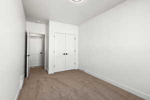 Unfurnished bedroom featuring carpet flooring and a closet