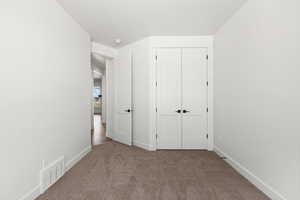 Unfurnished bedroom with dark carpet and a closet