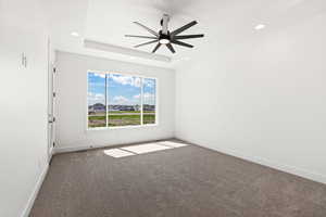 Unfurnished room with dark carpet, a ceiling fan, a raised ceiling, and recessed lighting