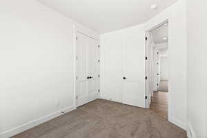 Unfurnished bedroom featuring dark carpet and a closet