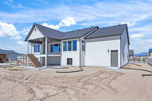 Rear view of house featuring a patio area, ceiling fan, stucco siding, and a shingled roof