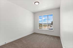 Carpeted spare room with baseboards