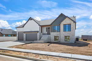 View of front facade featuring stone siding, a garage, driveway, and covered porch
