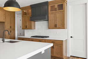 Kitchen with decorative backsplash, light stone counters, dark wood-style floors, wood finish cabinetry, and glass fronted cabinets