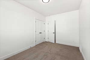 Empty room with dark carpet and baseboards