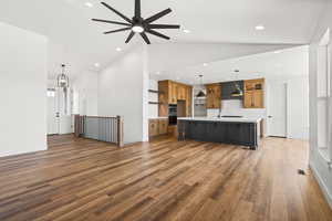 Unfurnished living room with lofted ceiling, ceiling fan, dark wood-style flooring, and a chandelier