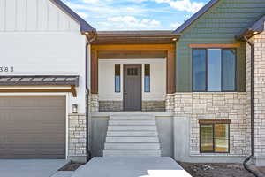 View of front of property featuring stone siding, a porch, board and batten siding, concrete driveway, and a garage