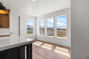 Unfurnished dining area with light wood-type flooring, a textured ceiling, recessed lighting, and a mountain view