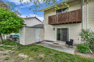 Back of property featuring a patio area, a balcony, and a lawn