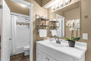 Full bathroom featuring vanity, shower / bath combination with curtain, and stone finish flooring