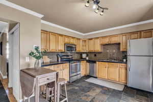 Kitchen with stainless steel appliances, light wood finish cabinetry, dark stone finish flooring, backsplash, and tile countertops