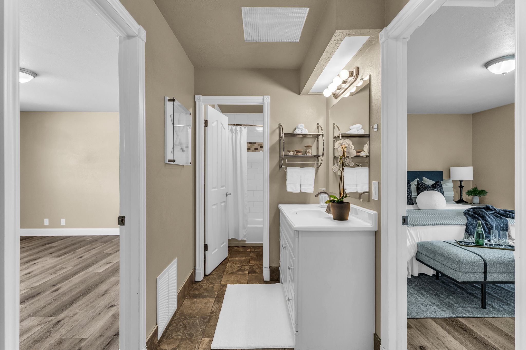 Ensuite bathroom with vanity, curtained shower, and dark stone finish flooring