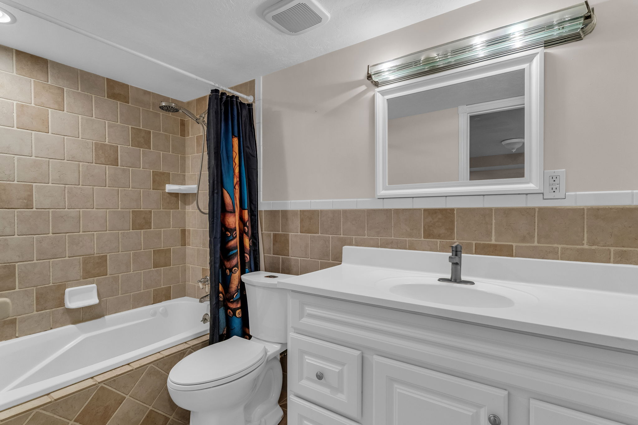 Full bathroom with vanity, shower / bath combo, and tile walls