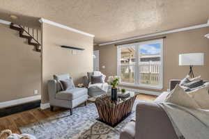 Living area with hardwood / wood-style floors, crown molding, and a textured ceiling