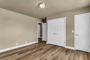 Unfurnished bedroom featuring wood finished floors and a closet