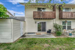 Rear view of property featuring a balcony, a patio area, and a yard