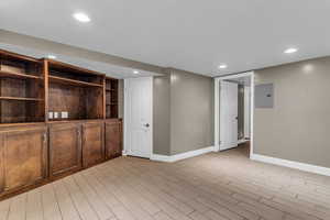 Finished below grade area with wood finish floors, electric panel, and recessed lighting
