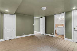 Unfurnished bedroom featuring recessed lighting, wood finish floors, and connected bathroom