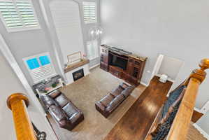Living room with a high ceiling, a brick fireplace, a chandelier, and dark wood-type flooring