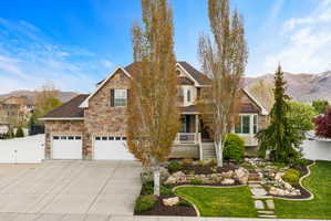 View of front of property featuring a mountain view, stone siding, driveway, covered porch, and a gate