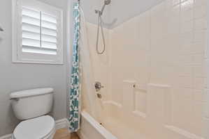 Full bathroom featuring toilet and shower / bath combo with shower curtain