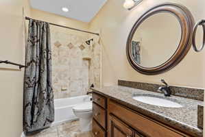 Bathroom featuring vanity, shower / bathtub combination with curtain, and light tile patterned flooring