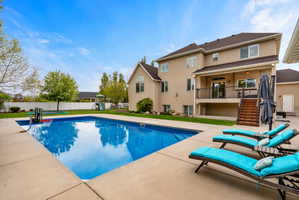 View of pool with patio surround, a balcony, and a fenced backyard