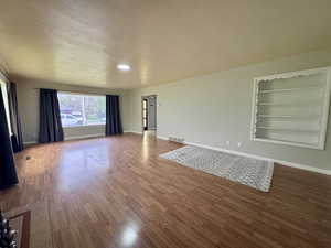 Main level living room with wood finished floors, built in shelves, and a textured ceiling