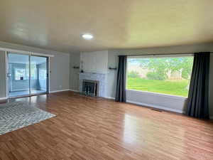 Main level living room featuring wood finished floors, a textured ceiling, and a fireplace