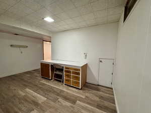 Basement office with light wood-type flooring and a drop ceiling