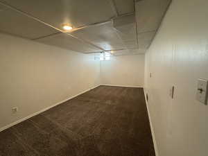 Basement bedroom with dark carpet and baseboards