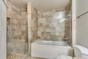 Full bathroom with a stall shower, a bath, and a textured ceiling