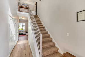 Stairway featuring wood finished floors and a high ceiling