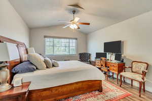 Bedroom featuring light wood finished floors, ceiling fan, and lofted ceiling
