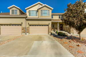 Craftsman-style house with stone siding, concrete driveway, an attached garage, covered porch, and stucco siding