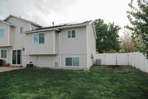Back of property featuring roof mounted solar panels, a fenced backyard, a patio, and a gate