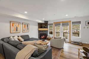Living room with plenty of natural light, a fireplace, wood finished floors, and recessed lighting