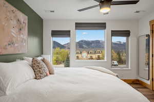 Bedroom featuring a mountain view, multiple windows, a ceiling fan, and wood finished floors