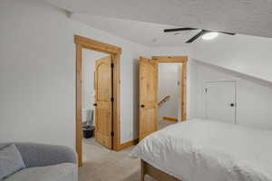 Bedroom with ceiling fan, light colored carpet, and ensuite bathroom