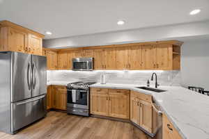 Kitchen featuring stainless steel appliances, light wood finished floors, light wood finish cabinetry, a kitchen breakfast bar, and recessed lighting