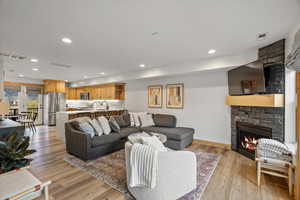 Living room with a fireplace, light wood-type flooring, and recessed lighting