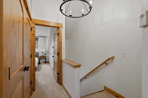 Hall featuring light colored carpet and a chandelier