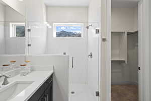 Full bath with a spacious closet, vanity, a stall shower, and light carpet