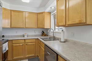 Kitchen with light countertops, stainless steel dishwasher, range with electric cooktop, and light wood finish cabinetry