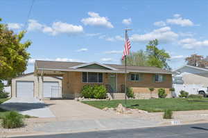 Single story home with an outdoor structure, brick siding, driveway, roof with shingles, and a garage