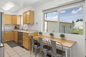 Kitchen featuring light countertops, stainless steel appliances, light wood finish cabinets, and light tile patterned floors