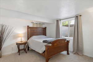 Bedroom with a textured ceiling and light carpet