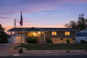 Ranch-style home featuring driveway, brick siding, an outbuilding, a porch, and a garage