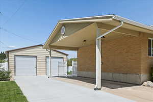 View of side of property with brick siding, a garage, an outdoor structure, and a carport