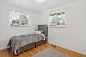 Bedroom with light wood finished floors and multiple windows